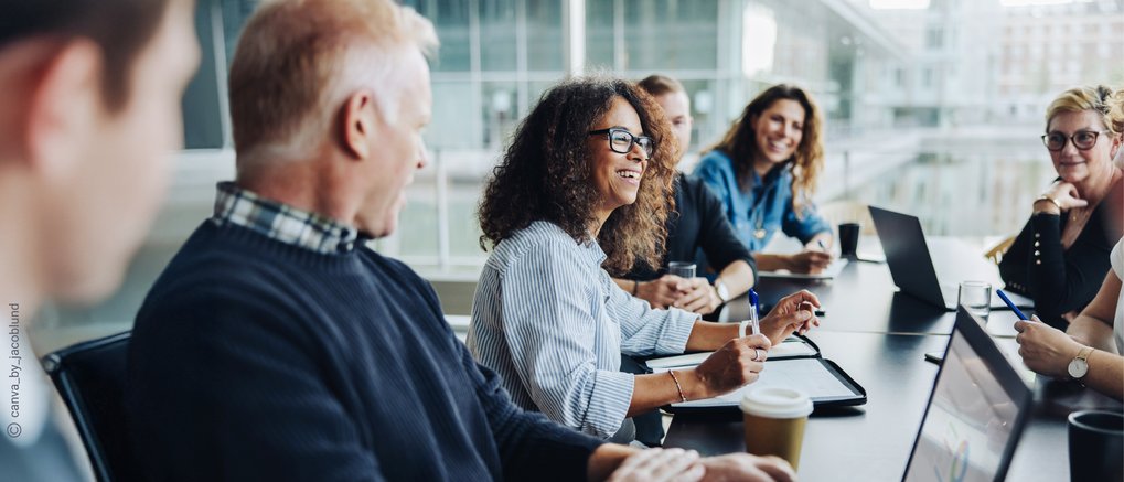 Diverse team members gathered in a modern office space, actively collaborating during a business meeting with digital devices and coffee cups on the table.