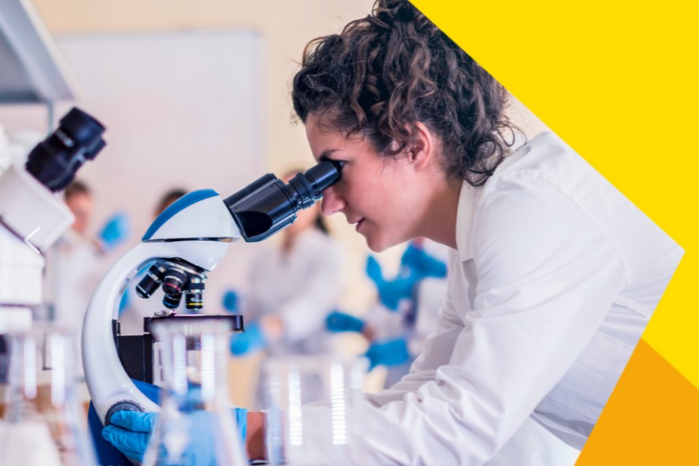 Wissenschaftlerin im weißen Kittel arbeitet im Labor mit Mikroskop und Flaschen.